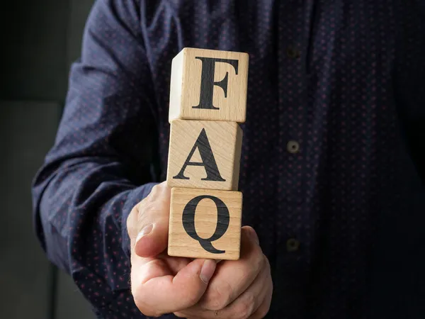 Człowiek trzyma kostki ze światem FAQ najczęściej zadawane pytania. — Zdjęcie stockowe
