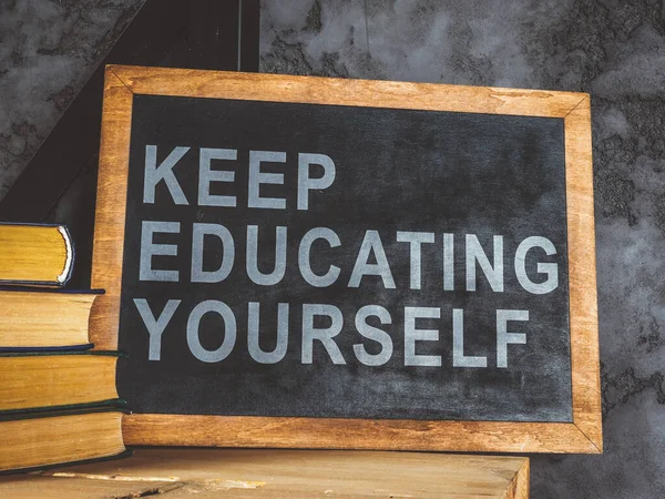 Blackboard near wall with words Keep educating yourself. — Stock Photo, Image