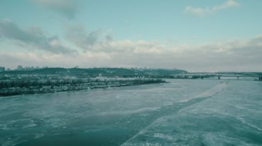 Winter landscape with a bridge and a river overlooking the city of Kyiv.
