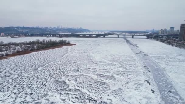 Flight over the frozen Dnieper River near the bridge overlooking the European city of Kyiv. — Stockvideo