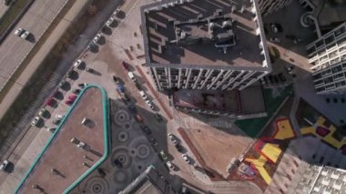 Top down flying over tall buildings and a road with cars. Winter city.