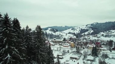 Panoramic view of a mountain valley with a small town surrounded by forest. Gloomy winter weather.