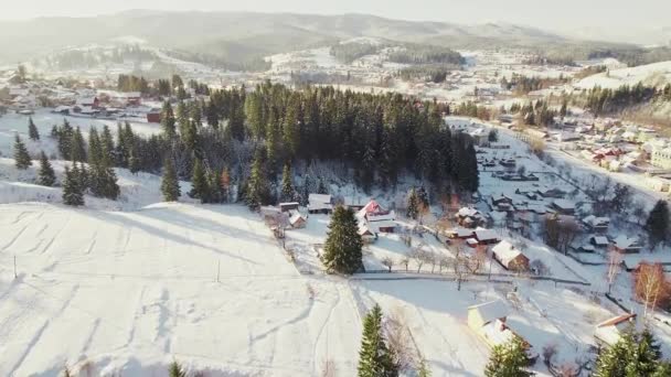 Aldeia coberta de neve em um vale de montanha. Aéreo em um dia ensolarado. — Vídeo de Stock