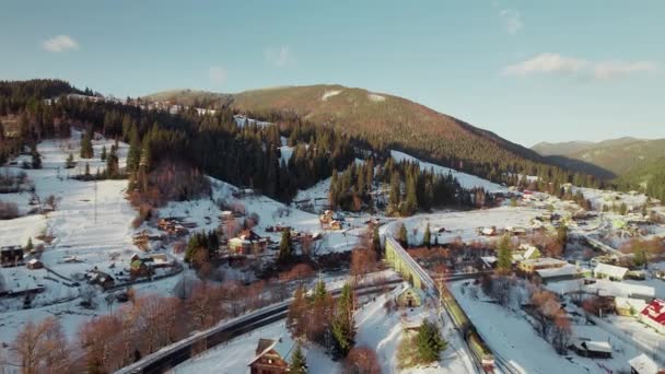 Voo sobre um trem que se move através de um vale de montanha no inverno. — Vídeo de Stock