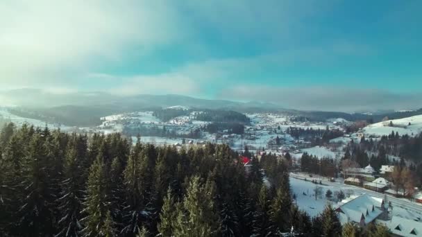 Paisaje soleado de invierno. Montañas y pueblo cerca del bosque. — Vídeo de stock