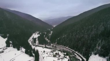 Dağlar arasındaki otomobil yolu ormanla kaplı. Bulutlu karanlık kış akşamı.