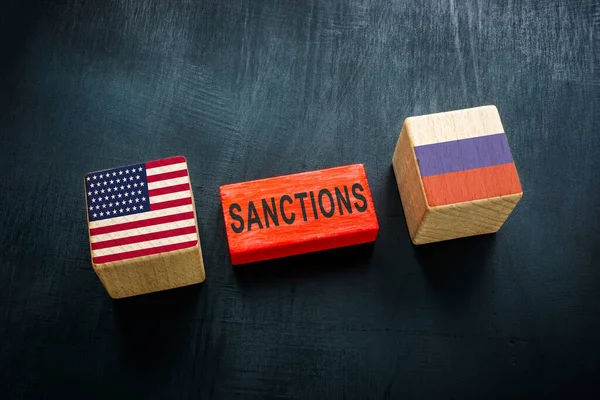 Cubi e bandiere di legno degli Stati Uniti e della Russia e sanzioni parola. — Foto Stock