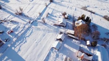 Kışın kırsal bölgelerde hava manzarası. Köy evleri ve karla kaplı bir tarla.