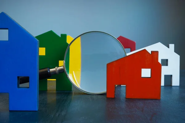 Inspección de la casa o concepto de selección. Edificios de colores y una lupa. — Foto de Stock