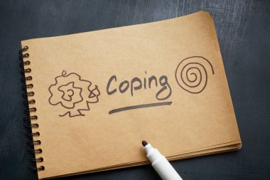 A notepad with an inscription coping lies on wooden surface.