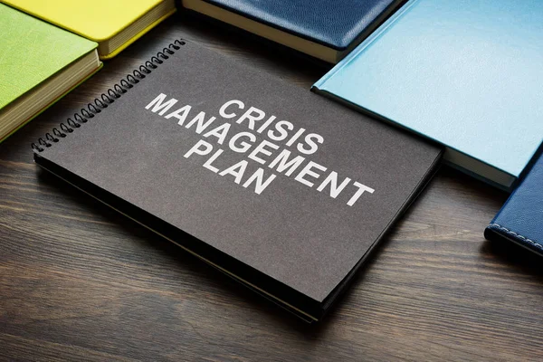 Crisis management plan and notepads on a desk.