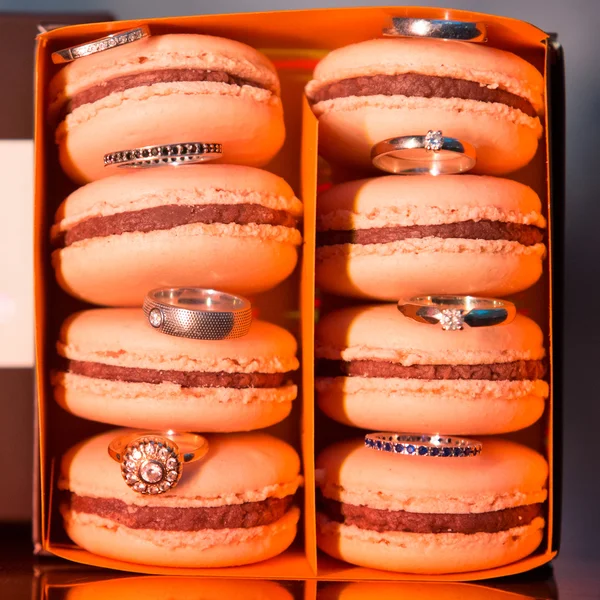 Macaroons coloridos e saborosos em caixa de papel com anéis de casamento — Fotografia de Stock