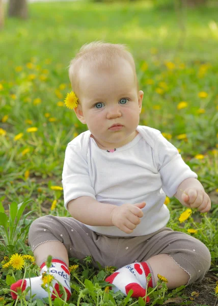 Jonge schattige vrolijke baby sit in park op groen gras en spelen — Stockfoto