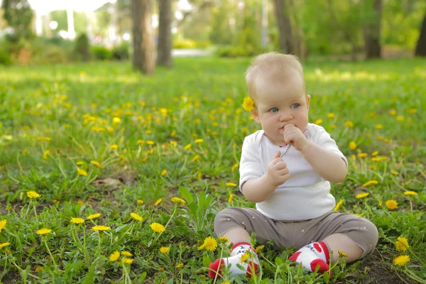 Young adorable cheerful baby sit in park on green grass and play — Stock Photo, Image