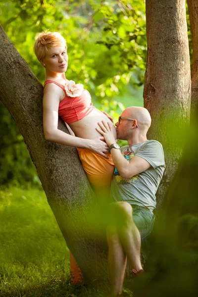 Glückliches junges schwangeres Paar, das sich in der Natur umarmt, neues Leben — Stockfoto