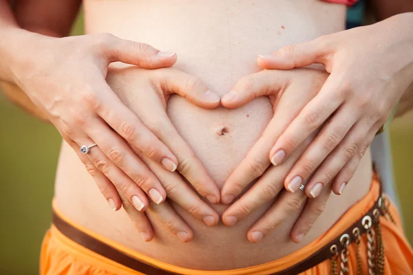 Paar erschafft mit den Händen ein Liebesherz - Schwangerschaft — Stockfoto