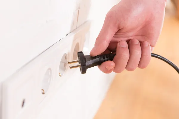 Stecker ziehen, Mann zieht schwarze Schnur und Stecker — Stockfoto