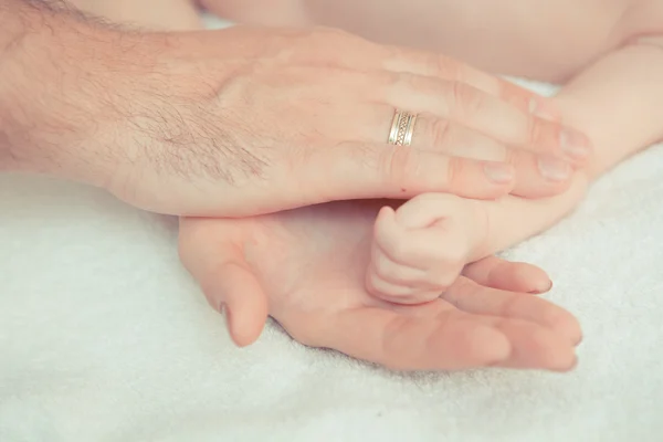 Madre y padre toman la mano del bebé — Foto de Stock