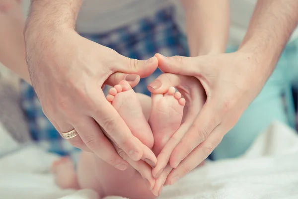 Mother and father hold feet of baby — Stock Photo, Image