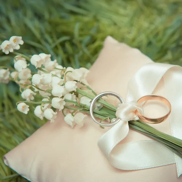 Anéis de casamento de ouro branco com um buquê — Fotografia de Stock