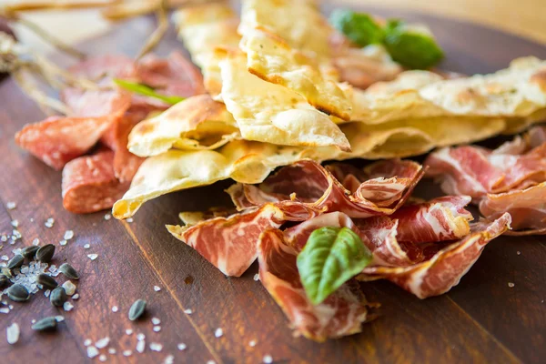 Homemade prosciutto and basil on a wooden board — Stock Photo, Image