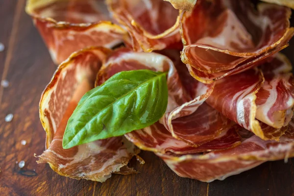 Homemade prosciutto and basil on a wooden board — Stock Photo, Image