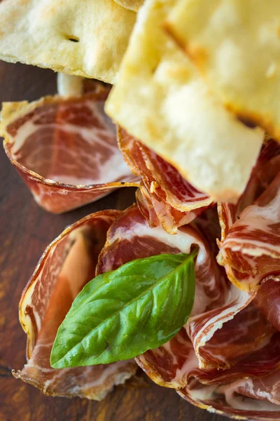 Prosciutto fatto in casa e basilico su tavola di legno — Foto Stock