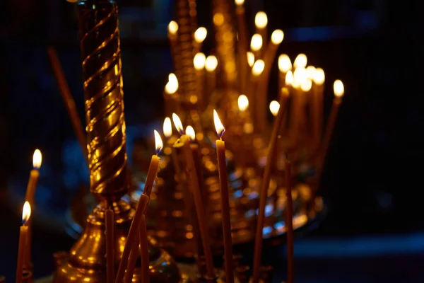 Religione e magia. Le candele stanno bruciando in una chiesa buia. Sullo sfondo c'è una misteriosa luce fioca e un vecchio lampadario — Foto Stock