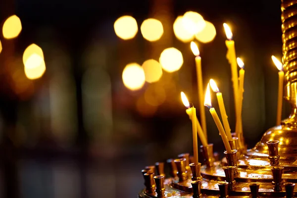 Religie en magie. Kaarsen branden in een donkere kerk. Op de achtergrond is een mysterieus schemerig licht en een oude kroonluchter — Stockfoto