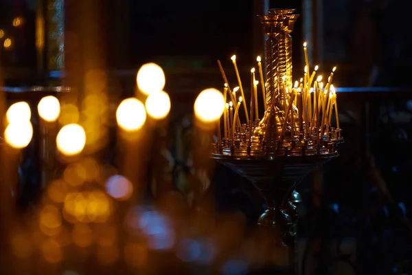 Religie en magie. Kaarsen branden in een donkere kerk. Op de achtergrond is een mysterieus schemerig licht en een oude kroonluchter — Stockfoto