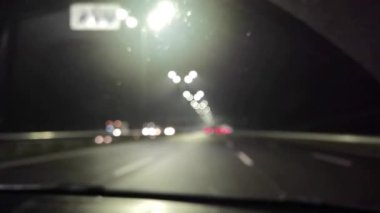 Gece şehirde araba trafiği, arabanın içindeki kamera. Gecenin karanlığında bulanık arkaplanda güzel, ışıl ışıl bir bokeh. Şehir caddesindeki trafik sıkışıklığında araba farlarından çok renkli bokeh ışıkları parlıyor..