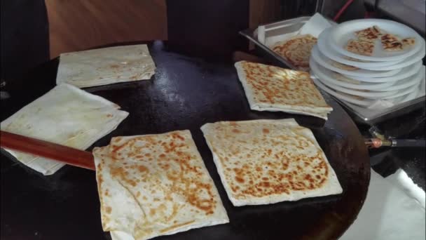 Uma mulher idosa cozinha tortilhas gozleme turcas tradicionais com carne ao ar livre — Vídeo de Stock