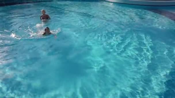 Dítě v bazénu cákající matku relaxaci. Kid hravě překvapit maminka rodina baví na slunečný den těší léto — Stock video