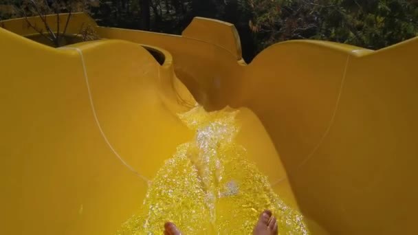 Unrecognizable male person riding water tube slide in aquapark. Speed water attraction. View on legs on playground. Slider travel down slide very quickly. Warm weather in recreational water parks — Stock Video