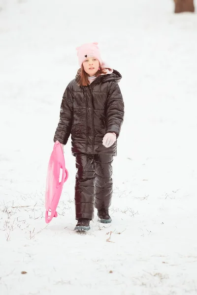 Menina feliz deslizando para baixo da colina em disco de trenó. Menina apreciando passeio deslizante na neve — Fotografia de Stock