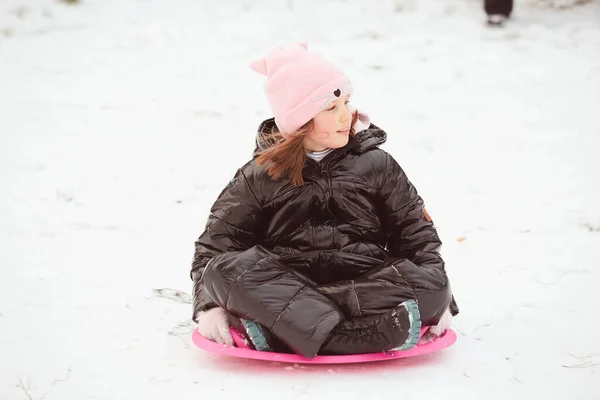 Actief meisje glijdt van de heuvel af. Gelukkig kind heeft plezier buiten in de winter op slee. Gezinstijd. — Stockfoto
