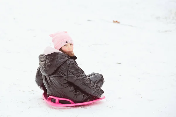 Menina ativa deslizando para baixo da colina. Criança feliz se divertindo ao ar livre no inverno no trenó. Tempo de família. — Fotografia de Stock