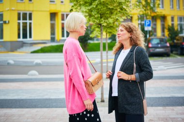 İki bayan arkadaş dışarıda gülüyor ve sarılıyorlar..