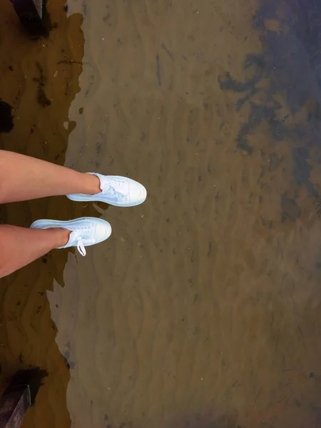 Las piernas de mujer sobre el agua en un muelle, el verano relajarse —  Fotos de Stock