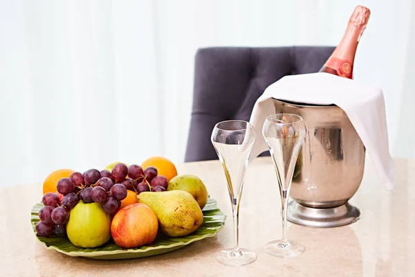 Champagne v hotelovém pokoji, ledové vědro, sklenice a ovoce na talíři - svatební koncept — Stock fotografie