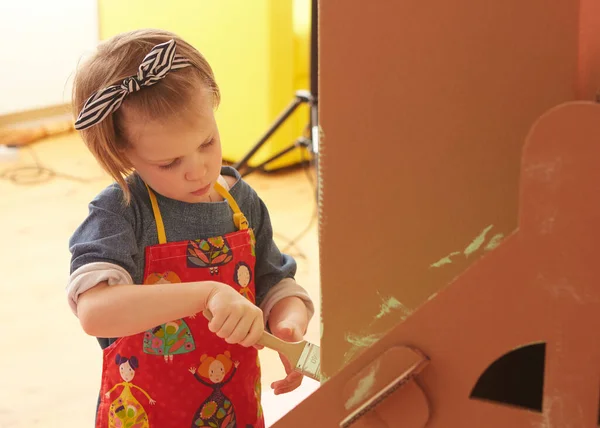 Side view of girl drawing on carton house and having fun at home. — Stok fotoğraf