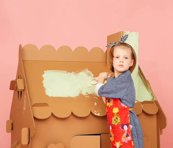 Side view of girl drawing on carton house and having fun at home. — ストック写真