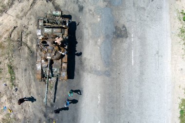 Kyiv region, Ukraine - May 15, 2022: War in Ukraine. Highway Kyiv - Zhytomyr. People take selfies against destroyed russian tank after russian atack in Febrary.