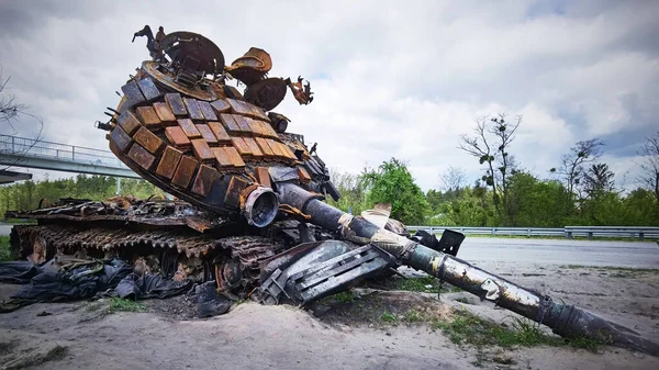 Kyiv region, Ukraine - May 15, 2022: War in Ukraine. Highway Kyiv - Zhytomyr. People take selfies against destroyed russian tank after russian atack in Febrary. — стоковое фото