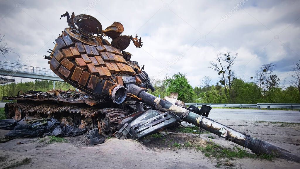 Kyiv region, Ukraine - May 15, 2022: War in Ukraine. Highway Kyiv - Zhytomyr. People take selfies against destroyed russian tank after russian atack in Febrary.