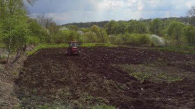 Traktörün üstünde toprağı süren bir çiftçi görüntüsü. Baharda tarım işi.
