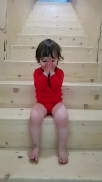 小女孩穿着红色的衣服坐在室内的楼梯上 — 图库视频影像