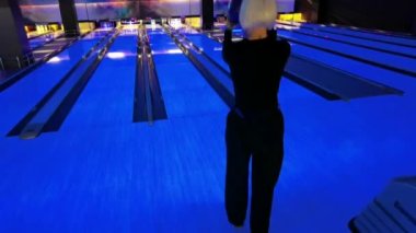 Bir kadın piste bowling topu atıyor..