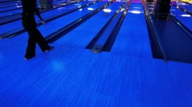 Bir kadın piste bowling topu atıyor..