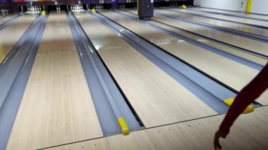 Bir kadın piste bowling topu atıyor.